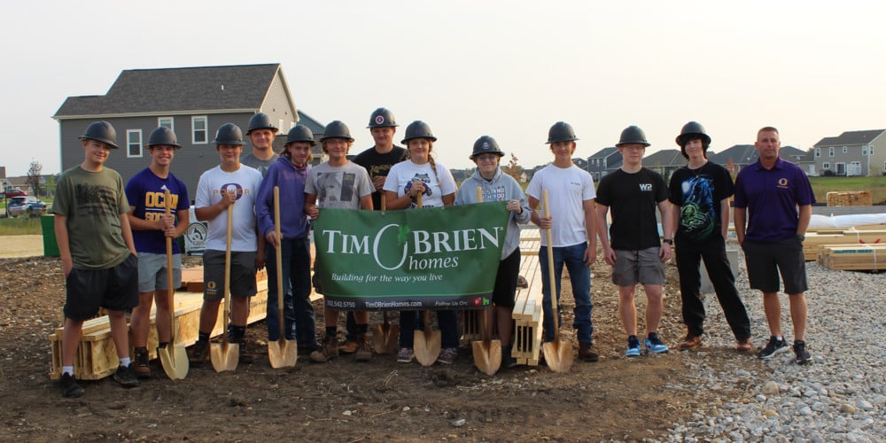 Students with shovels and construction hats with Tim O'Brien Homes